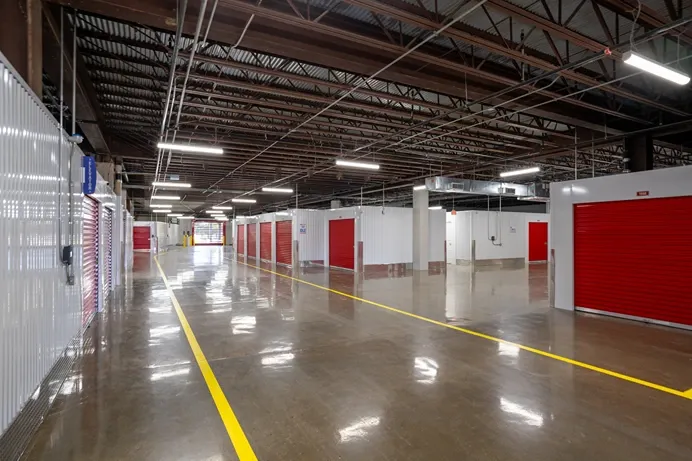 Indoor drive-through storage area with red roll-up doors and wide vehicle access lanes